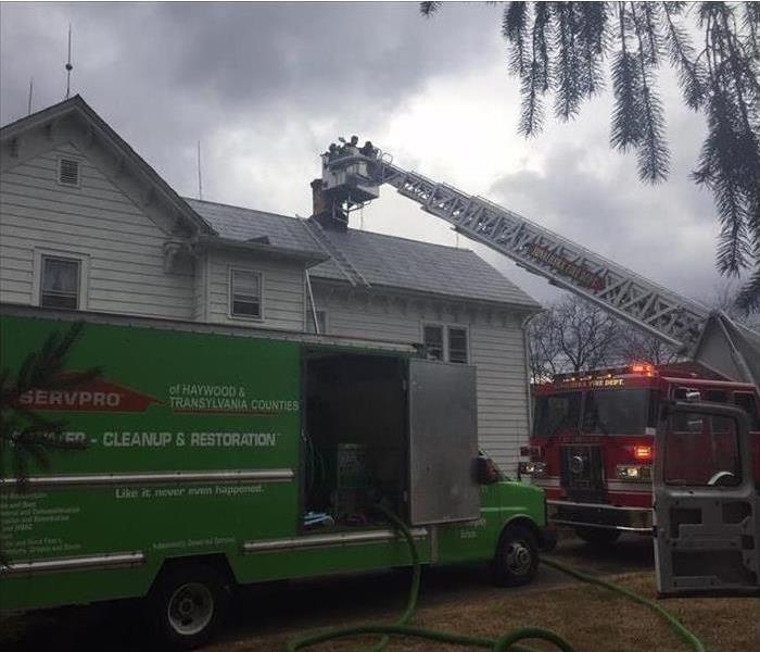 Green van and firefighters parked outside a house